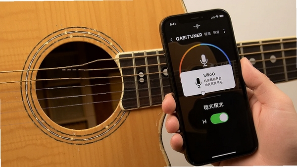 QABILTUNER移动端使用场景,用户手持手机靠近吉他音孔进行调音,屏幕显示麦克风权限开启提示与稳定模式开关,强调权限设置与优化技巧