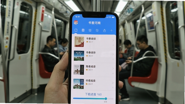 书香河南APP离线下载管理界面,手机屏幕显示已缓存书籍列表与下载进度条,背景为地铁车厢场景,突出离线阅读的便利性