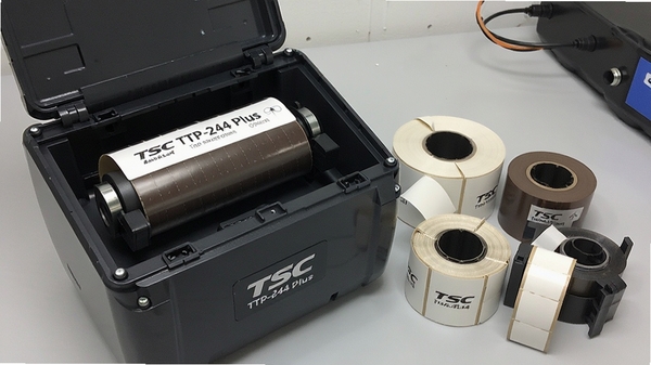 ��TSC TTP-244 Plus��ӡ����̼���ָǣ�չʾ�ڲ��ṹ���Ա߷����Ų�ͬ���ı�ǩ����̼����ǿ����Ĳļ�����ǿ���ص㣬��������չʾ��ӡ���ڲ����졣
