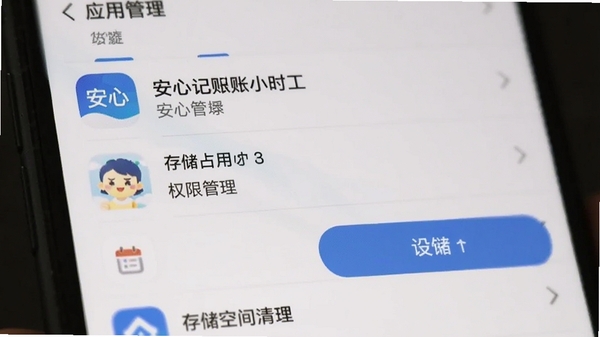 手机设置界面中应用管理列表,找到安心记账小时工应用图标,点击进入显示存储占用与权限管理选项,背景虚化,突出设置按钮和存储空间清理选项