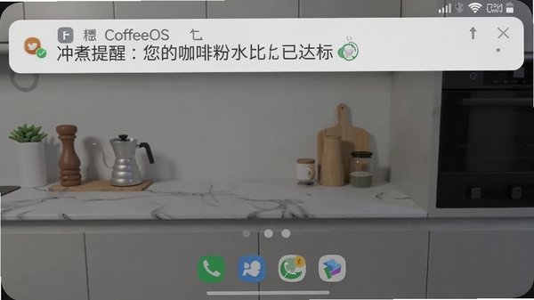 一张CoffeeOS应用在手机后台运行的截图,同时展示应用的通知栏消息,内容为“冲煮提醒:您的咖啡粉水比已达标”,背景为现代简约的厨房操作台