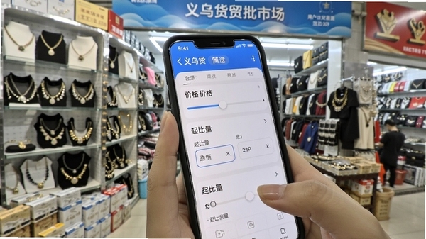 义乌货源批发市场APP中用户正在使用筛选功能查找低价饰品货源,手机屏幕显示价格滑块与起批量选项,背景是义乌商贸城档口货架,画面明亮清晰,突出便捷找货体验